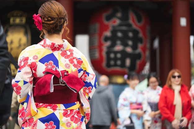 Jong meisje die Japanse kimono dragen die zich voor Sensoji-Tempel in Tokyo bevinden