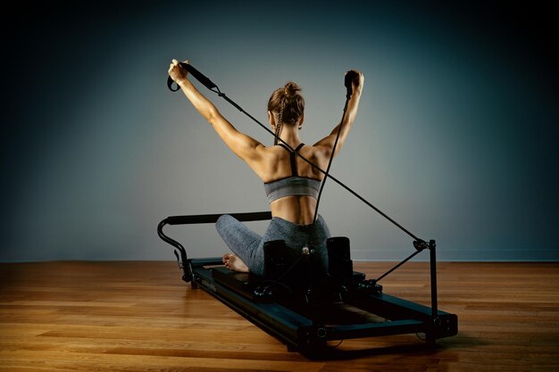 Jong meisje doet pilates oefeningen met een reformer bed mooie slanke fitness trainer op reformer