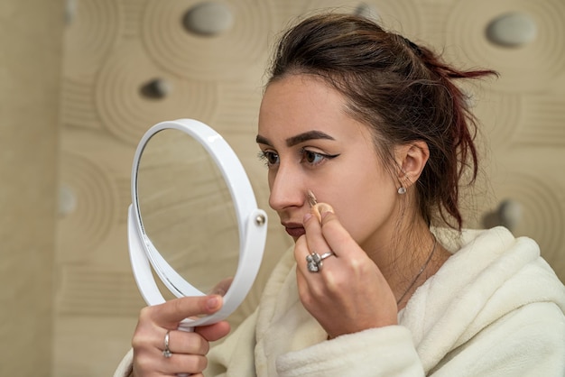 Foto jong meisje doet 's avonds make-up voor zichzelf in de badkamer in huiskleding. make-upconcept voor vrouwen