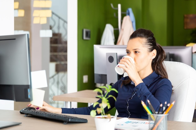 Jong meisje drinkt koffie op kantoor. ga op de stoel staan