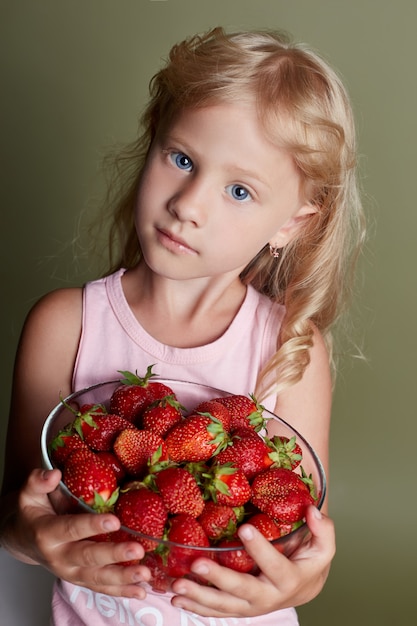 Jong meisje eet aardbeien, vrolijke emoties