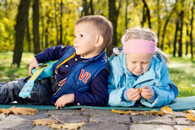 Jong meisje en kleine jongen met speelgoed gitaar genieten van vrije tijd in een park