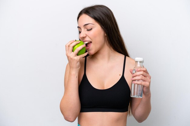 Jong meisje geïsoleerd op een witte achtergrond met een fles water en het eten van een apple