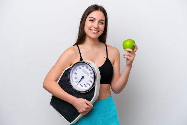 Jong meisje geïsoleerd op een witte achtergrond met weegmachine en met een apple