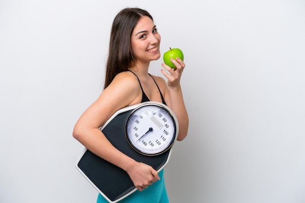 Jong meisje geïsoleerd op een witte achtergrond met weegmachine en met een apple