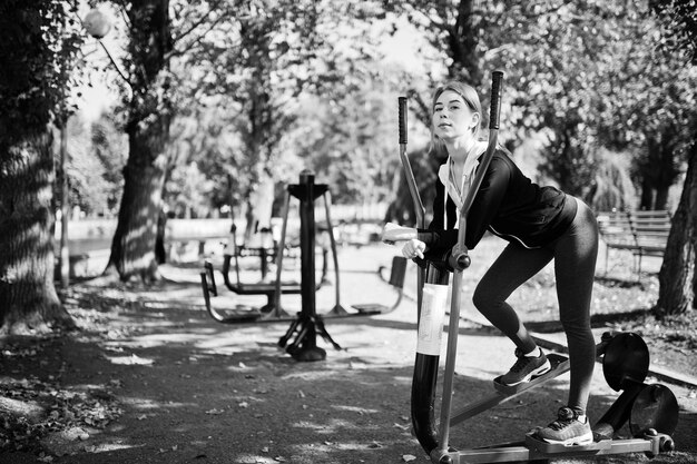 Foto jong meisje heeft de training en doet buiten oefeningen op straatsimulators sport fitness street workout concept