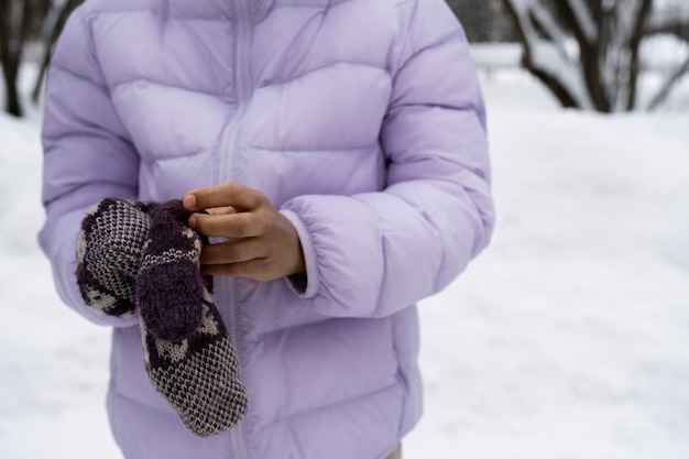 Foto jong meisje houdt haar handschoenen vast op een besneeuwde winterdag