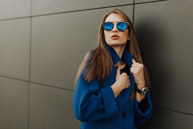 Jong meisje in blauwe jas staande op grijze achtergrond