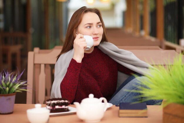 Jong meisje in café zit en drinkt thee met dessert