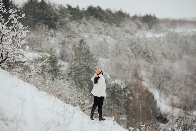 Jong meisje in de besneeuwde bergen met hoge sparren bedekt met sneeuw. Reis concept.