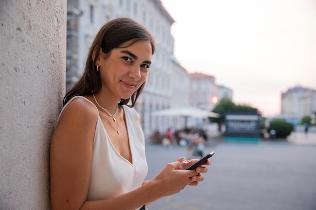 Jong meisje in de stad leunend tegen een berichtenpaal met haar mobiele telefoon