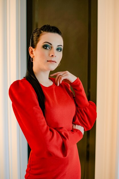 Jong meisje in een rode jurk binnenshuis. Nadenkend model. Emoties van een moderne dame. vrouw portret. Portret.