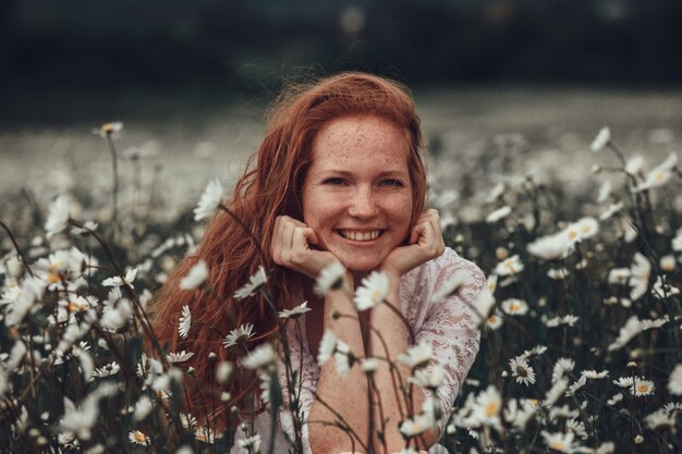 Foto jong meisje in een witte jurk in kamille veld