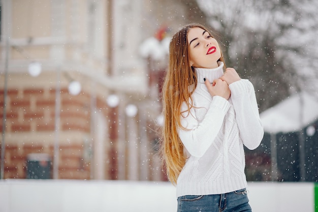 Jong meisje in een witte trui die in een winterpark staat