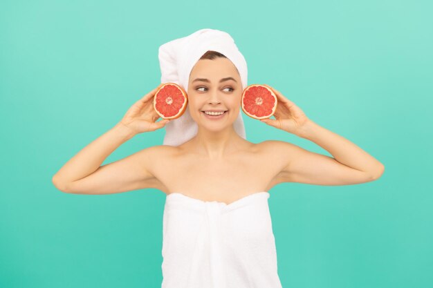 Jong meisje in handdoek na douche met grapefruit op blauwe achtergrond huidgezondheid