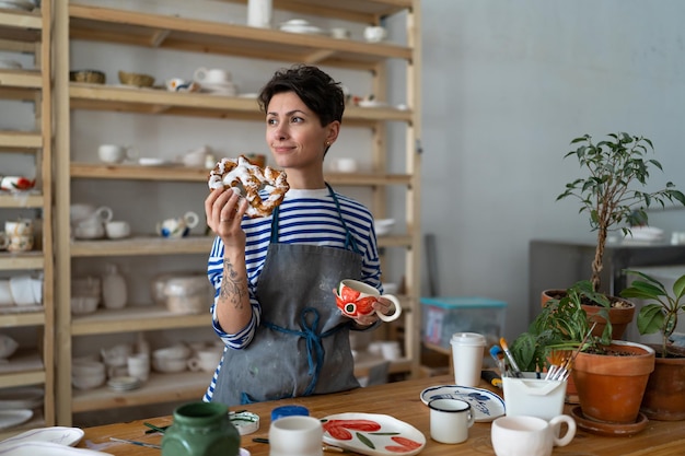 Foto jong meisje keramiek drinkt koffie en heeft een snack in de kunststudio tijdens de pauze van de masterclass