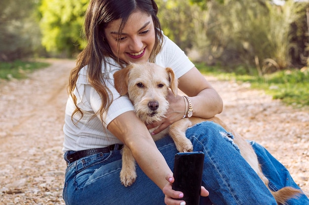 Jong meisje knuffelt haar hond en maakt een foto met haar mobiele telefoon