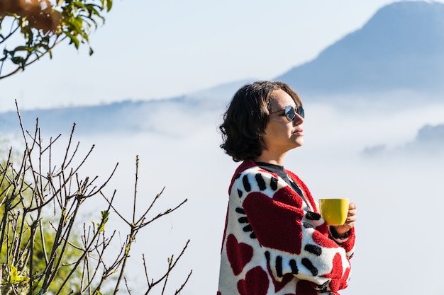jong meisje koffie drinken uit een mok op koude dag te veel mist en wolken bedekken het uitzicht op de stad