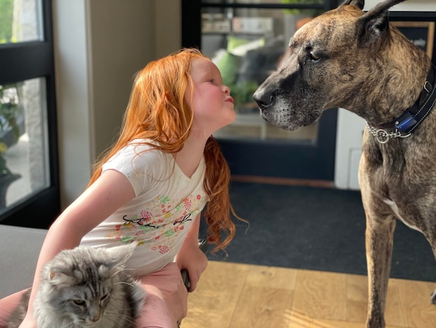 Foto jong meisje kussen met een hond thuis de kat kijkt op