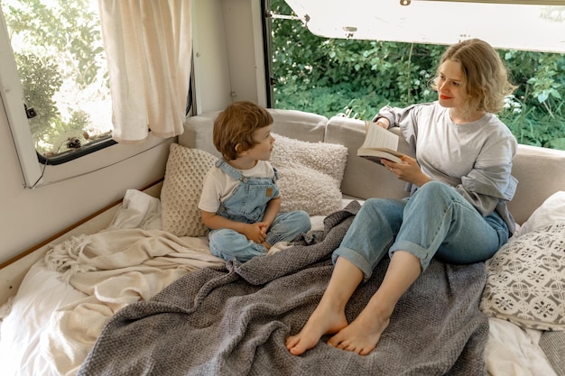 jong meisje leest papieren boek voor aan haar broer in een camper