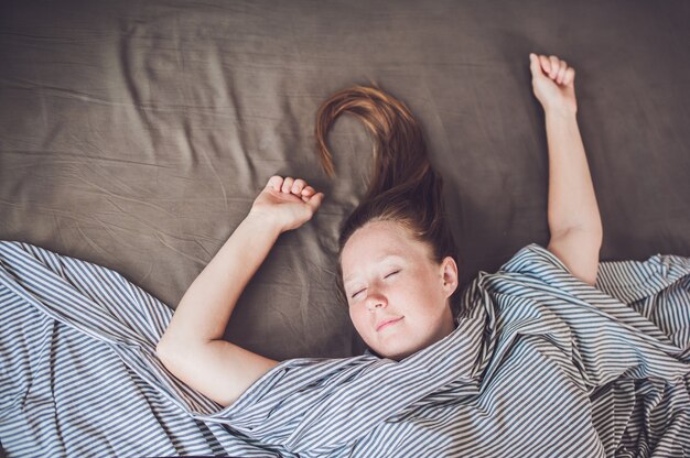 Jong meisje liggend in bed onder een deken