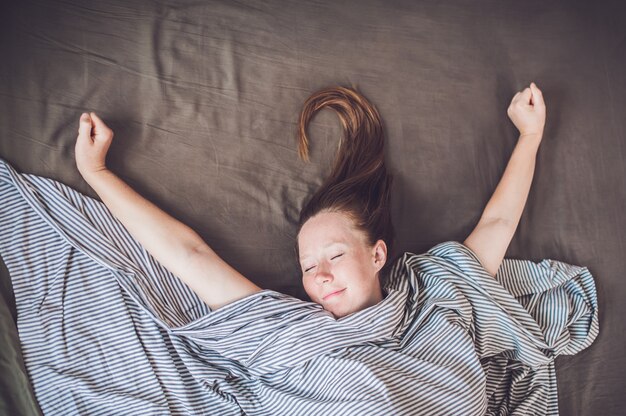 Jong meisje liggend in bed onder een deken