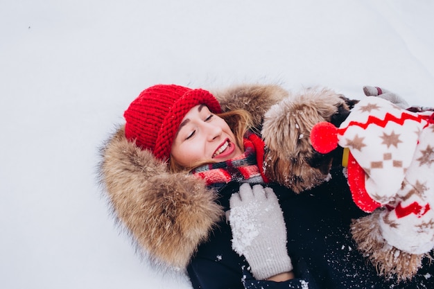 Jong meisje loopt in de lagere bossen in de winter met hond die een kerstmuts draagt