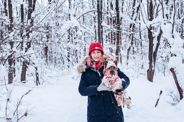 Jong meisje loopt in de lagere bossen in de winter met hond die een kerstmuts draagt