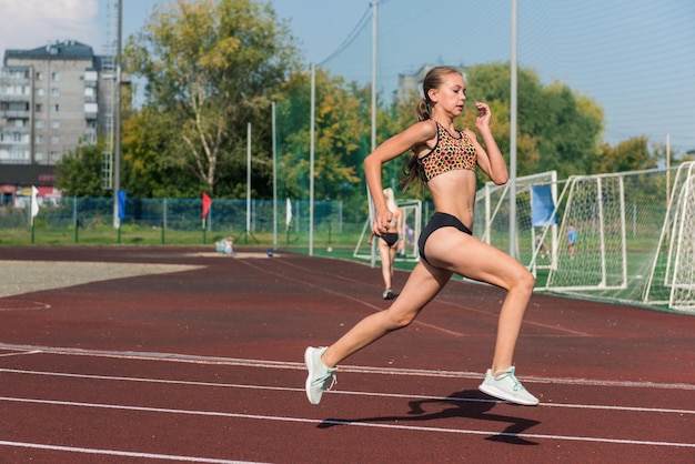 Jong meisje loopt op de atletiekbaan in het stadion buiten