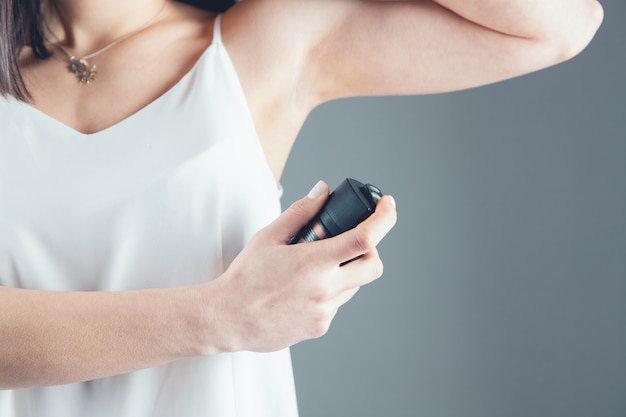 Jong meisje met aerosol deodorant op grijs