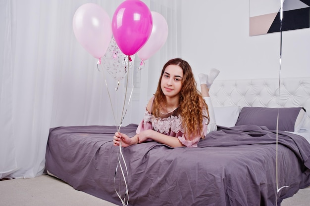 Jong meisje met ballonnen op bed gesteld op studio kamer