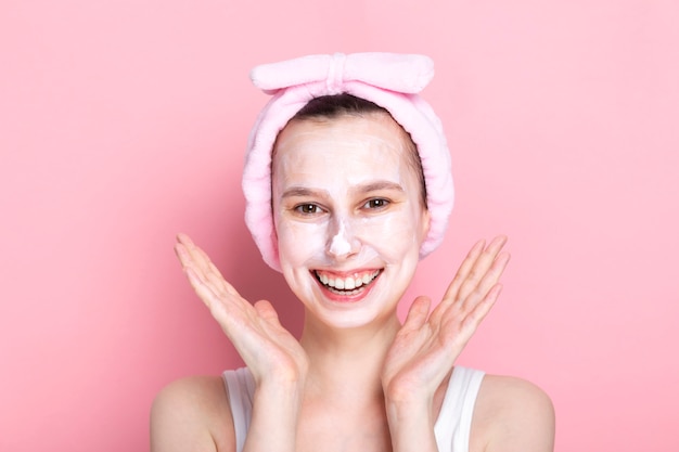 Jong meisje met cosmetische masker op haar gezicht en brede glimlachen