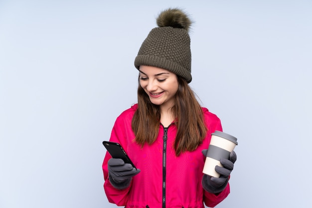 Jong meisje met de winterhoed dat op blauw wordt geïsoleerd