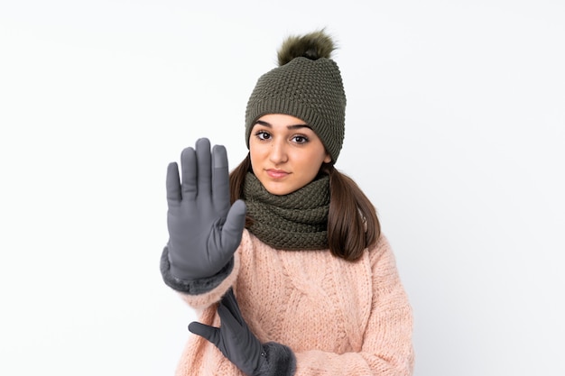 Jong meisje met de winterhoed over geïsoleerd wit makend eindegebaar met haar hand