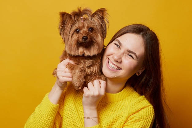 Jong meisje met een hond Yorkshire terrier op een gele schone achtergrond