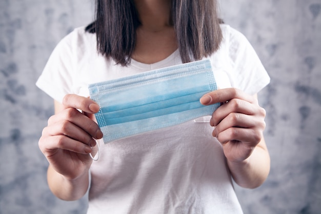 Jong meisje met een medisch masker op een grijze achtergrond