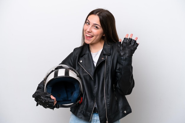 Jong meisje met een motorhelm geïsoleerd op een witte achtergrond die met de hand salueert met een gelukkige uitdrukking