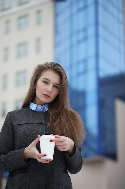 Jong meisje met een papieren kopje koffie buiten