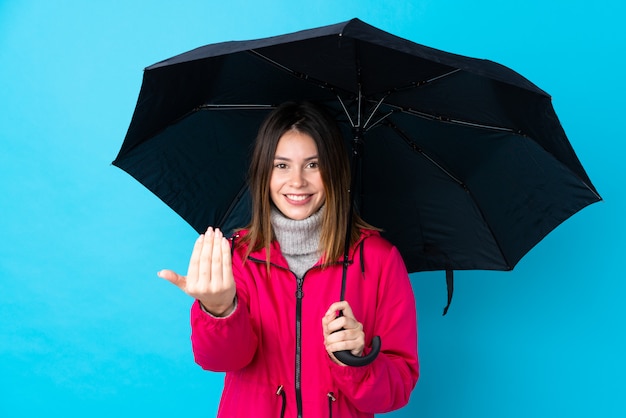 Jong meisje met een paraplu over blauwe muur