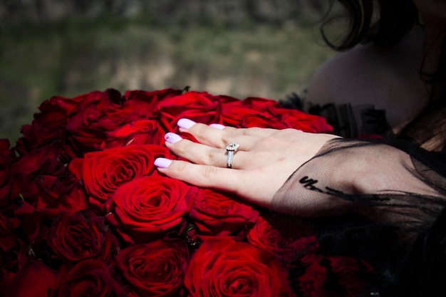 Jong meisje met haar hand met een trouwring op een boeket rozen