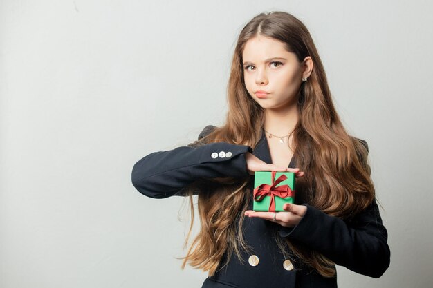 Jong meisje met kleine groene geschenkdoos op witte achtergrond.