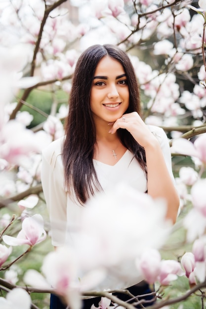 Jong meisje met magnoliabloesem. Mooie jonge vrouw in de buurt van de lente bloemen boom.