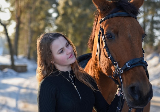 Jong meisje met paard op winter forest road.