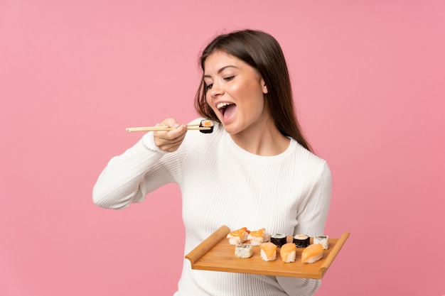 Jong meisje met sushi over geïsoleerde roze achtergrond