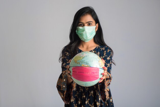 Jong meisje met wereldbol met een geneeskunde gezichtsmasker. wereldepidemie van coronavirus concept.