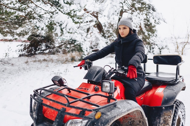 Jong meisje op een motorfietsritten in snow-covered pijnboombos in de winter