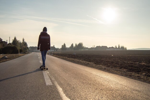 Jong meisje op het longboard. Zonsondergang landschap. Vrije tijd.