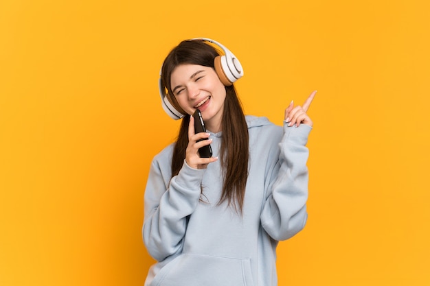 Jong meisje over geïsoleerde het luisteren muziek met mobiel en het zingen