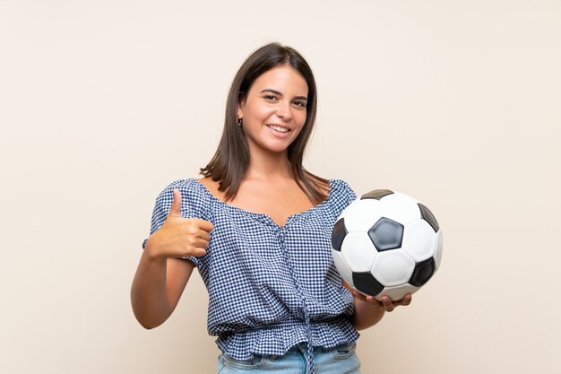 Jong meisje over geïsoleerde muur die een voetbalbal houdt