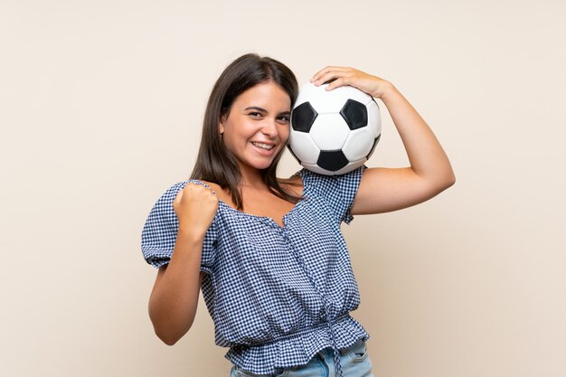 Jong meisje over geïsoleerde muur die een voetbalbal houdt